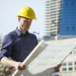 Building contractor wearing hard hat looking at blueprint