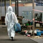 Inspector female worker hazmat suit holding chemistry tank in industrial.