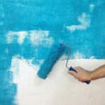 Painting the wall with blue paint and a roller. Renovation concept.